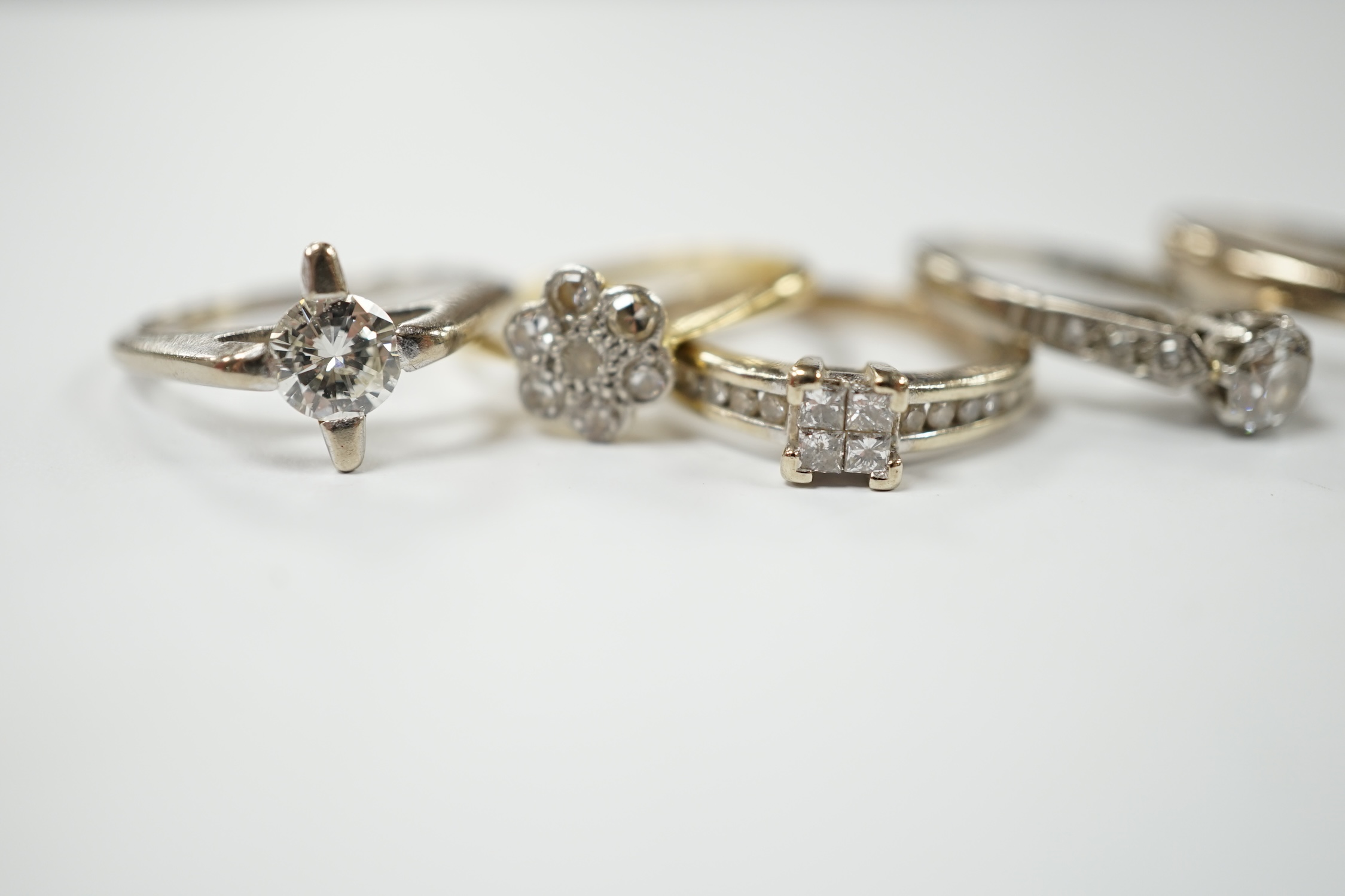 Four assorted 18ct, plat and diamond rings, including two solitaires and a flower head cluster, together with a modern 9ct and diamond cluster ring. Condition - fair